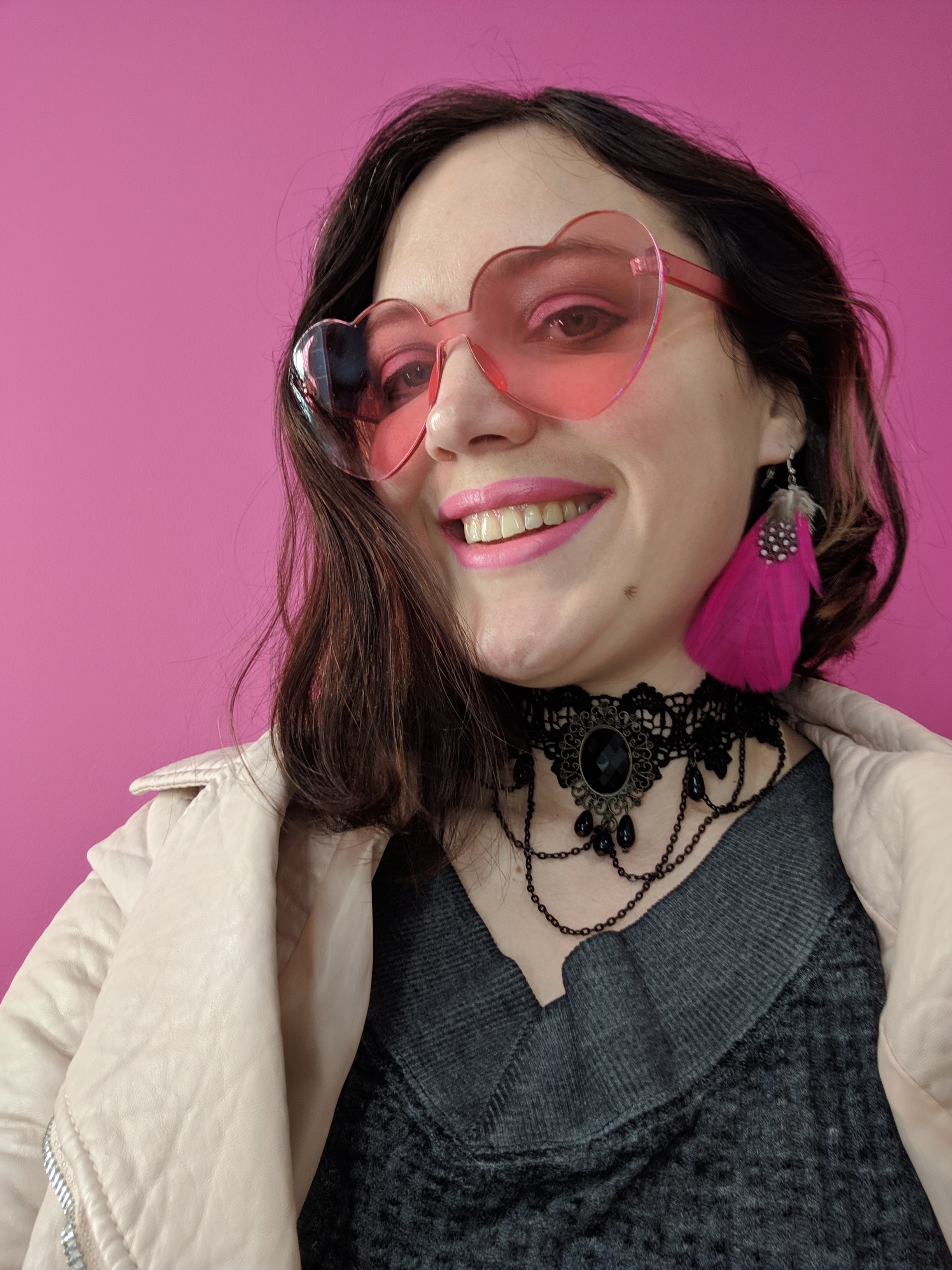 A picture of me wearing pink heart sunglasses against a pink backdrop