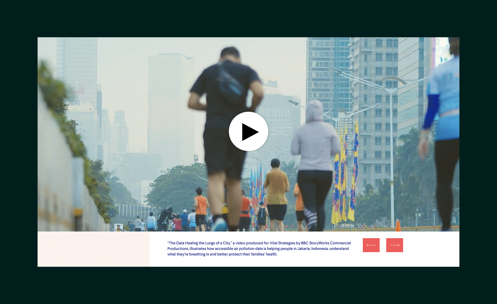 People jogging and walking on a city street with tall buildings and colorful flags in the background during daylight.