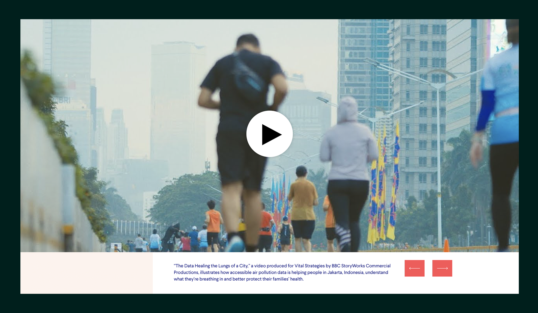 People jogging on a city street with tall buildings and colorful flags in the background.