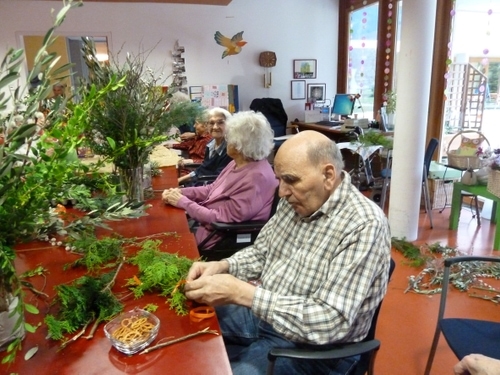 Älterer Mann sitzt an Tisch und bastelt
