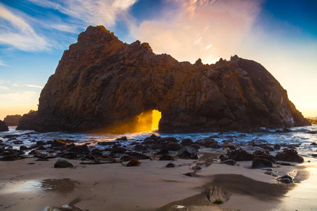 A keyhole arch of rock on the beach.