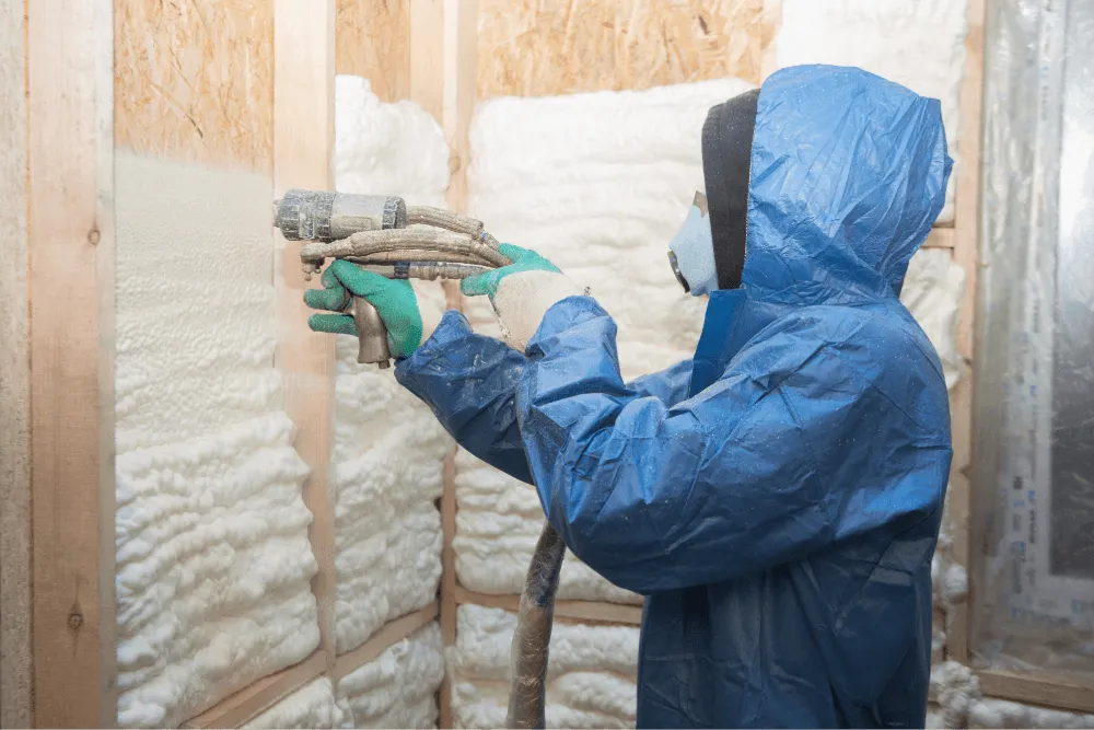 Technician applying spray foam insulation in an attic