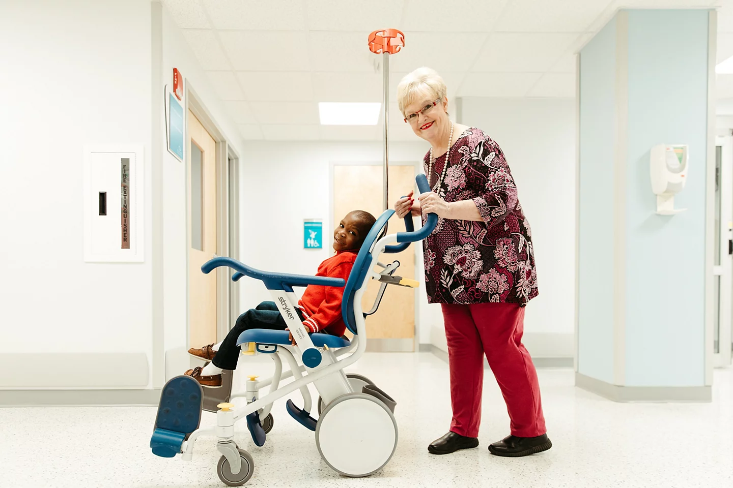 Volunteer transfering young smiling patient in premium mobility chair. 