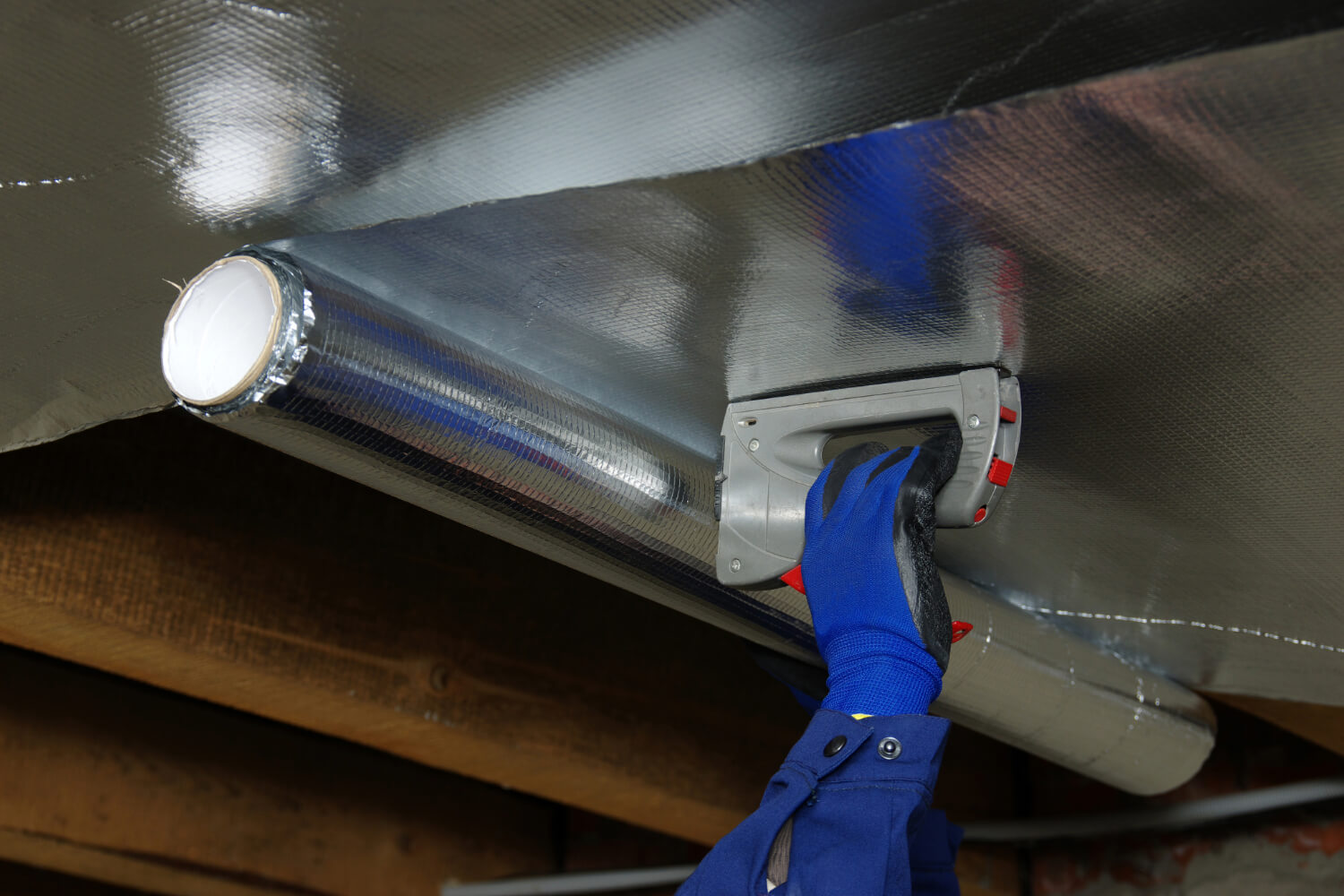 Person installing radiant barrier insulation.