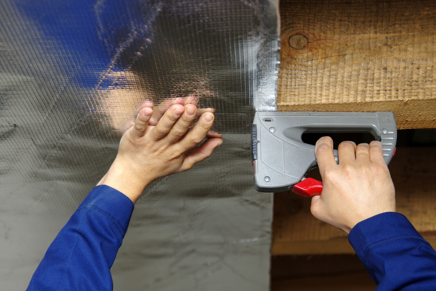 Person installing radiant barrier in attic.