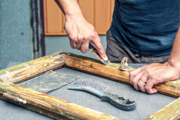 Person repairing wooden window frame.