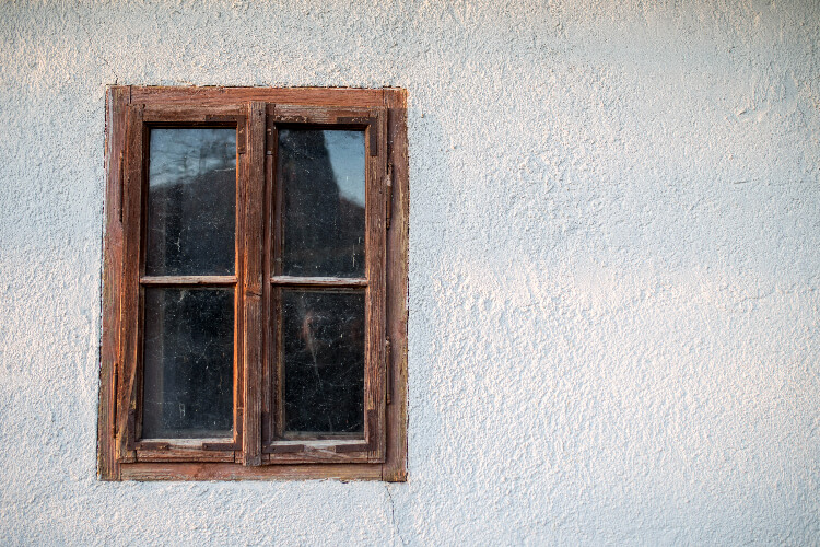 Old wooden window on beige stucco wall.