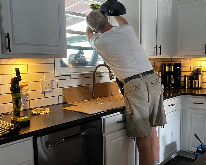 Man installing window in kitchen