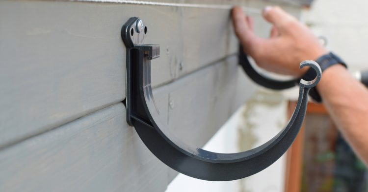 Person installing window awning brackets.