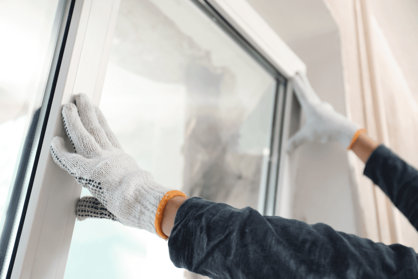 Person installing a new modern window frame wearing white gloves.