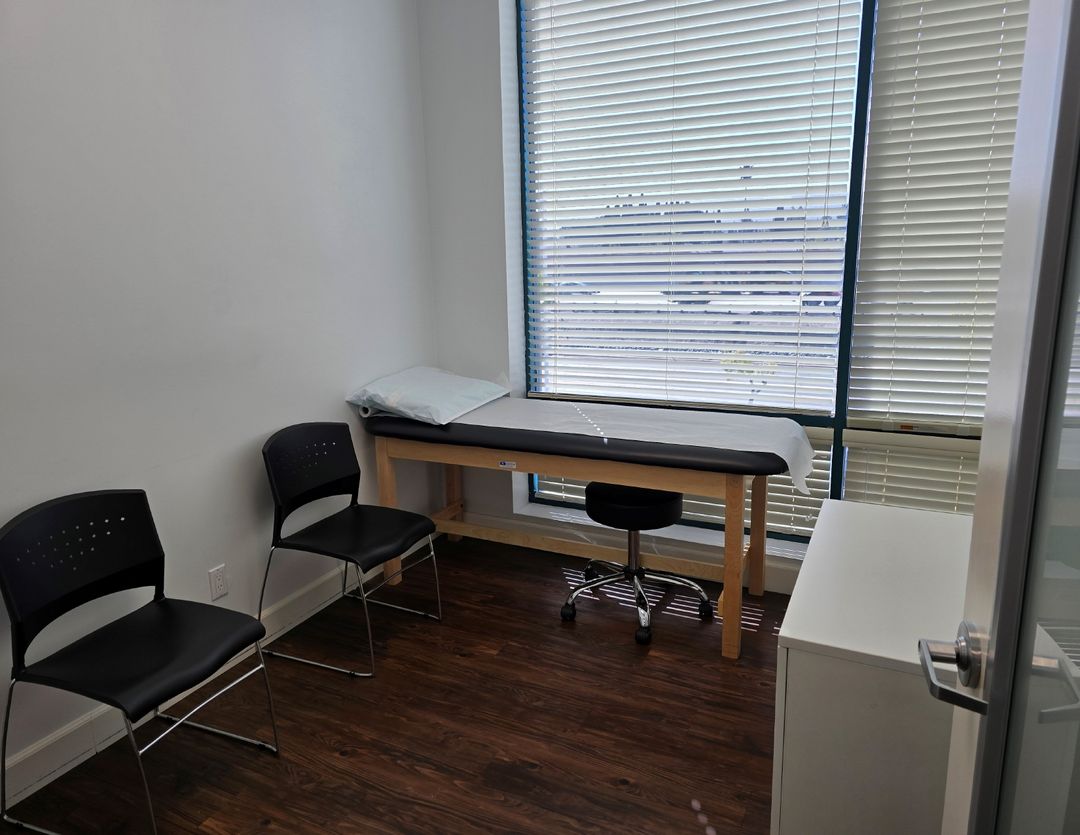 Exam room with a treatment table, chairs and a large window