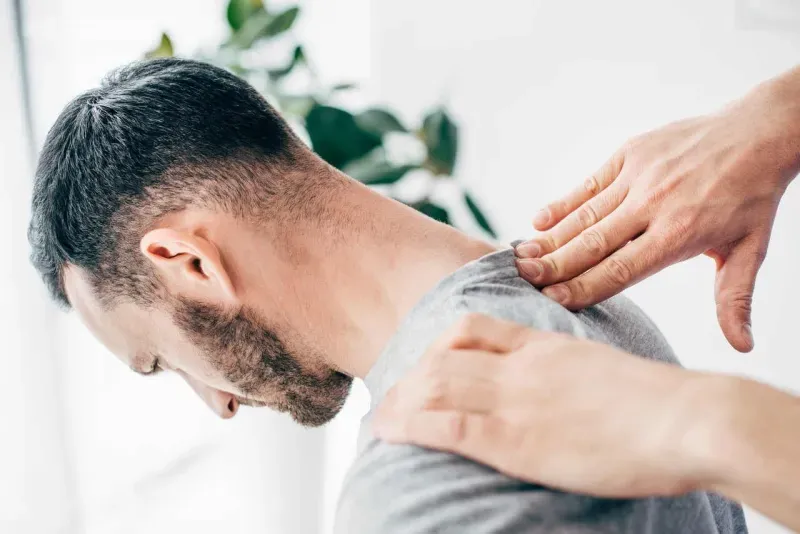 Clinician's hands supporting a man's neck and shoulder