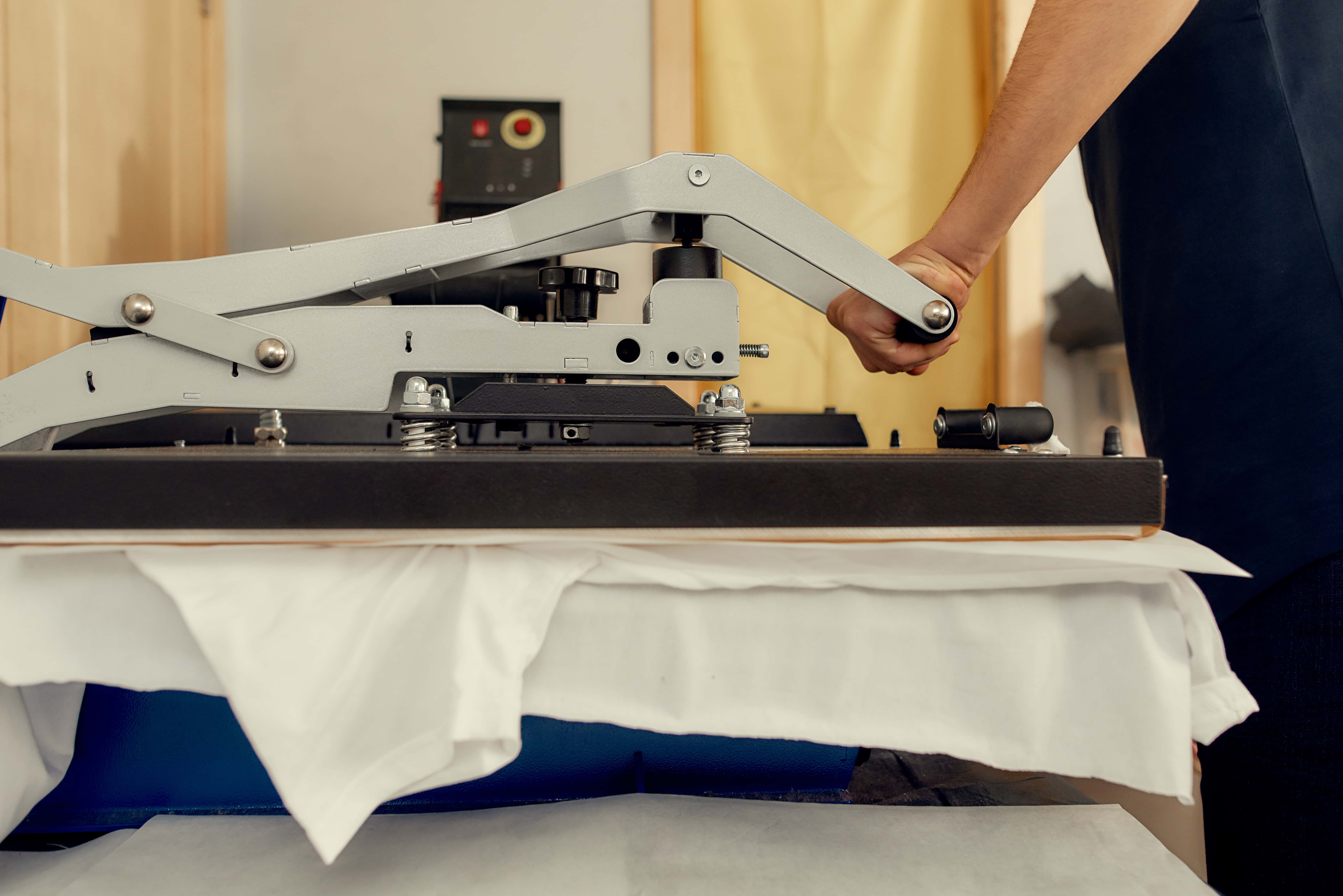 A t-shirt in a press receiving a customized design.