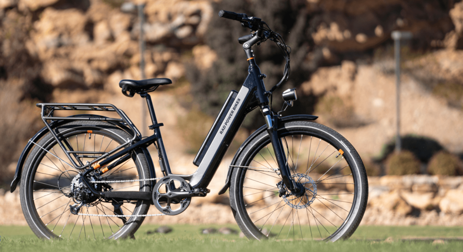 Blue and white electric bicycle with rear rack on grassy rocky background