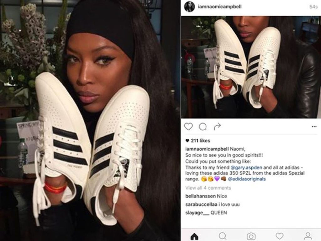 Woman holding white Adidas 350 SPZ sneakers with black stripes