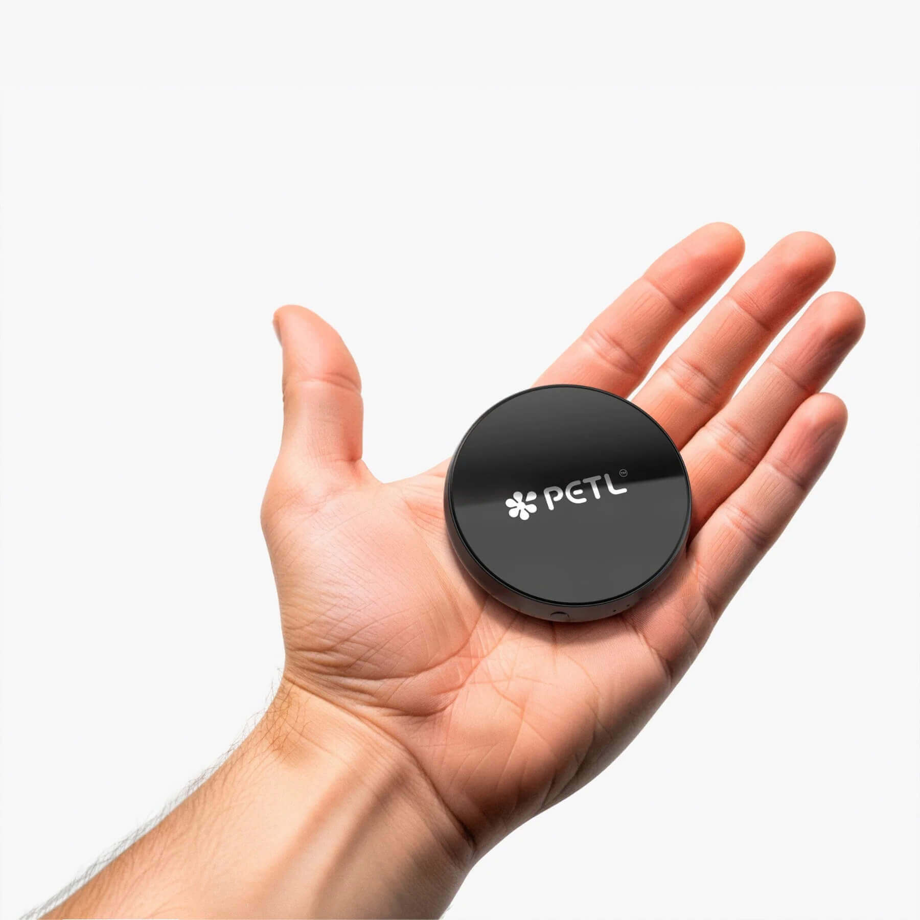 Black PETL device held in an open palm against white background