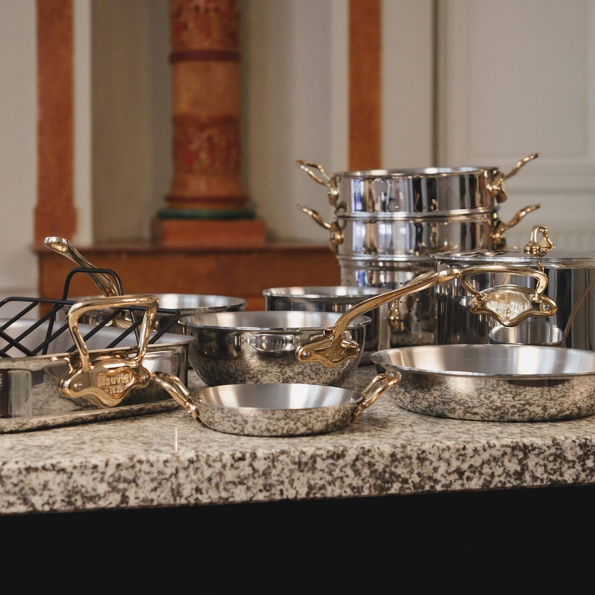 Luxury stainless steel cookware set with gold handles on granite countertop