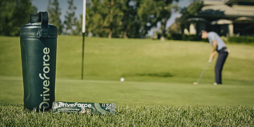 Driveforce water bottle and energy bar on golf course with golfer in background