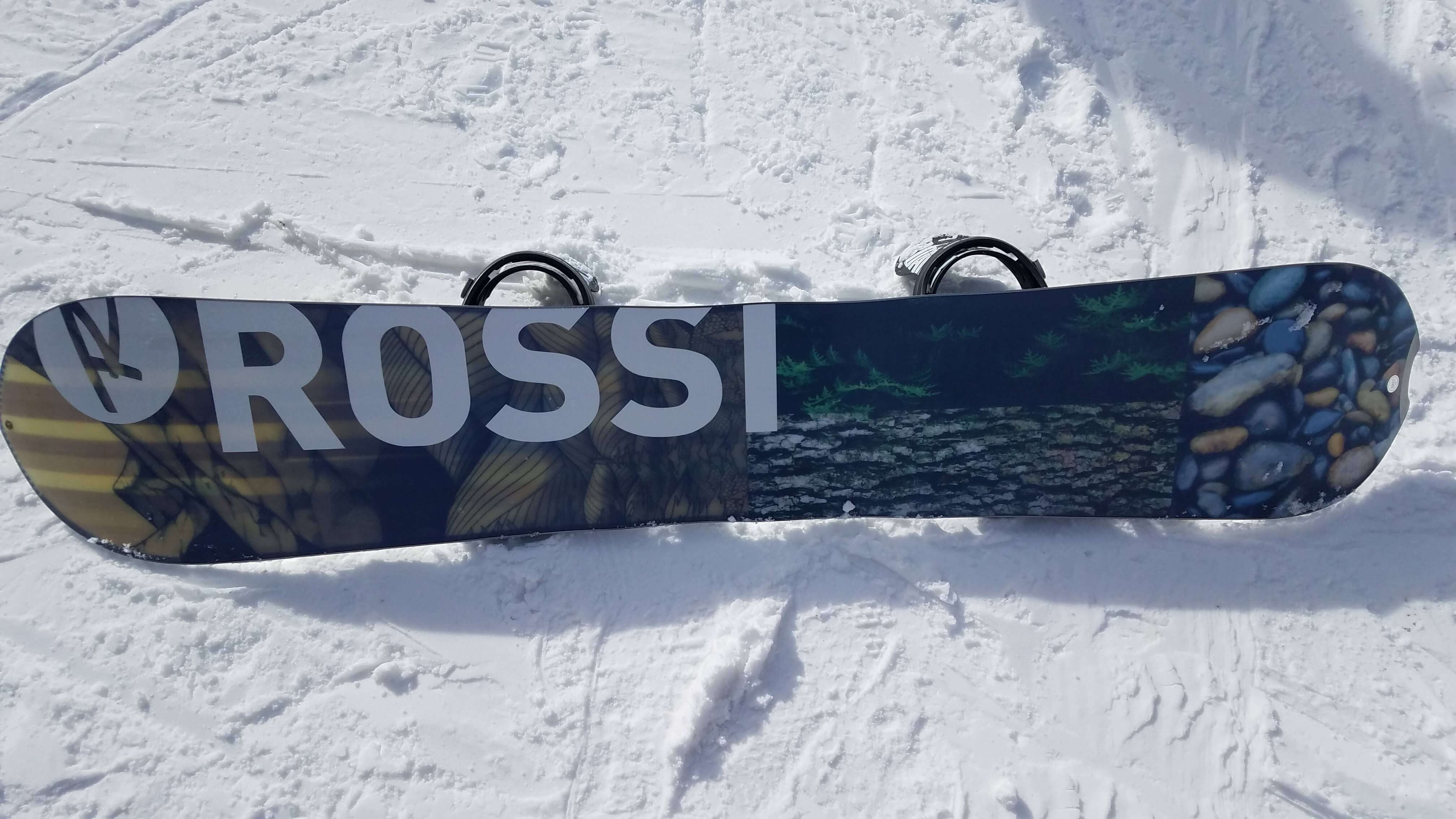 Rossi snowboard with artistic design lying on snow-covered ground