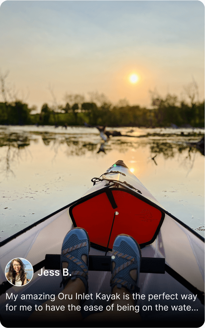 Kayak on calm water at sunset with person's feet in blue shoes