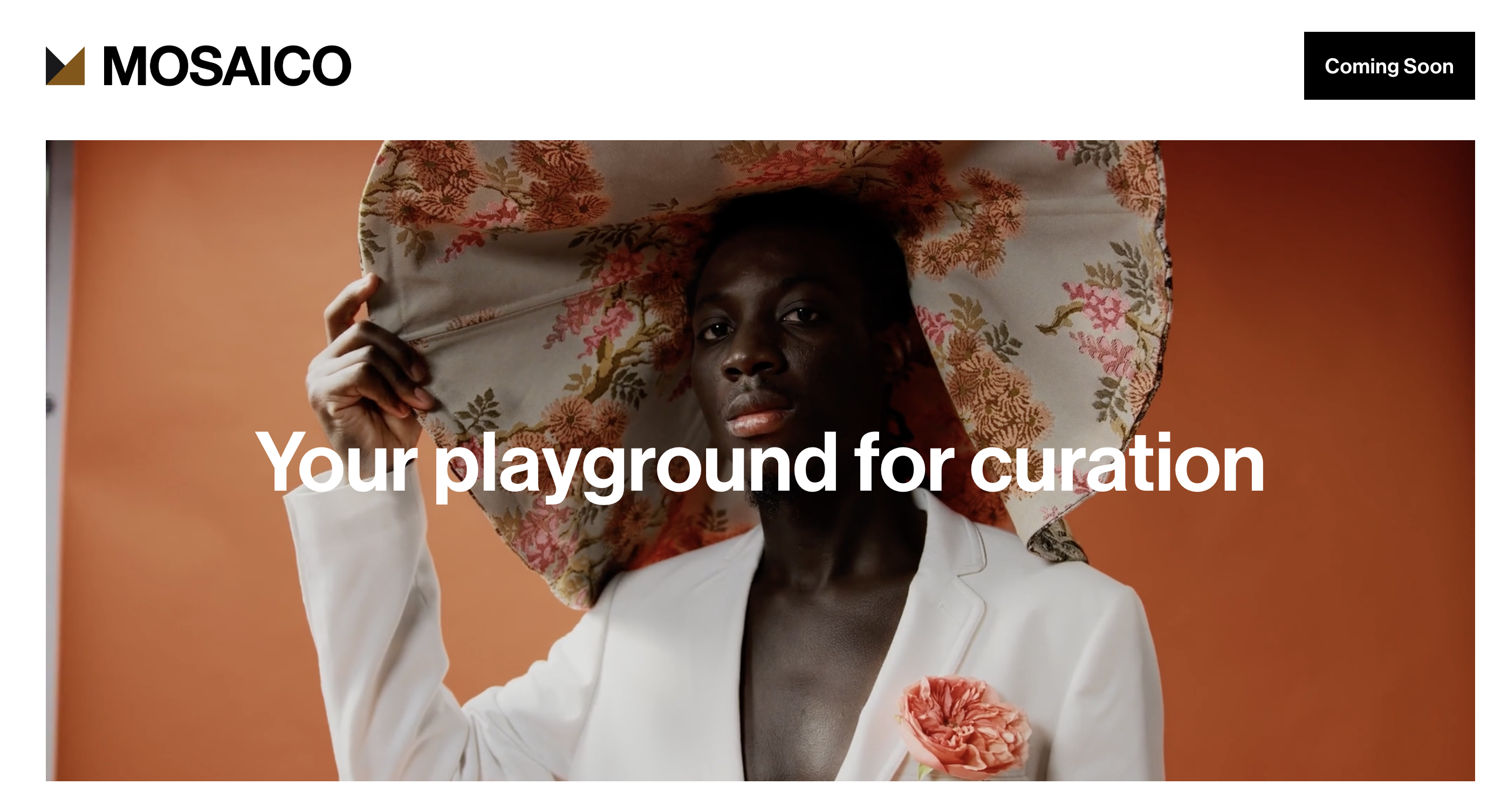 Person in white suit holding floral umbrella against orange background