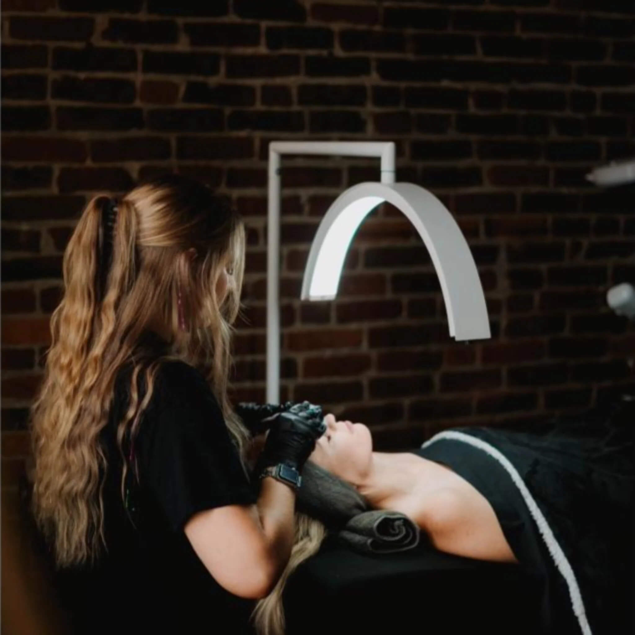 Professional tattooing session with artist working on client against brick wall