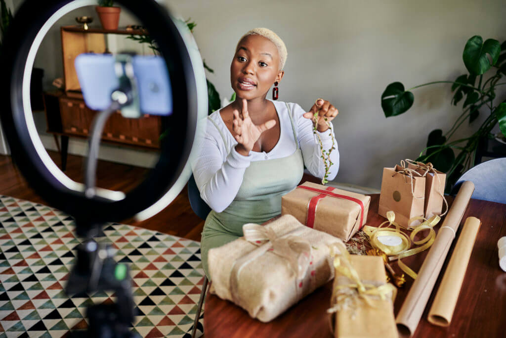 Woman recording gift wrapping tutorial with ring light and presents