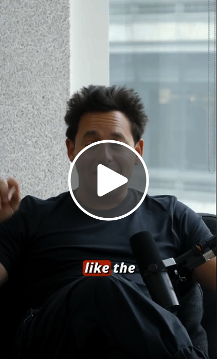 Person in black shirt with play button, looking thoughtful near window