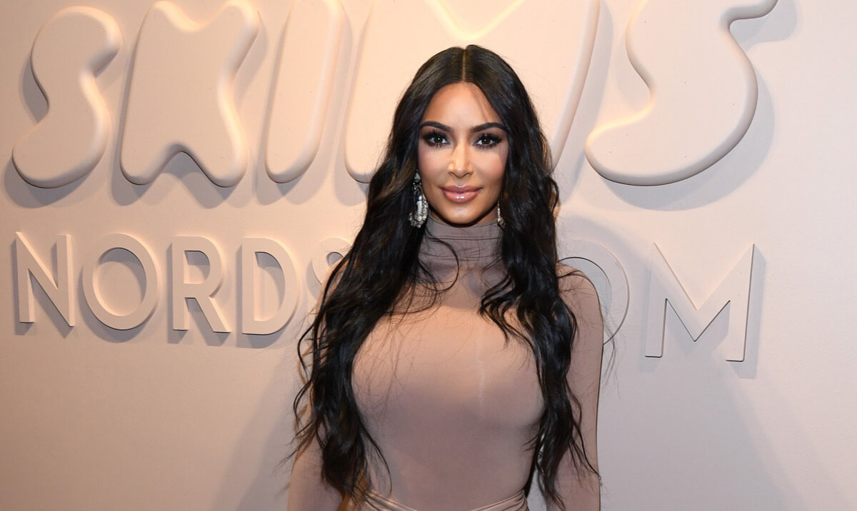 Person with long dark hair posing at Nordstrom event in neutral-toned outfit