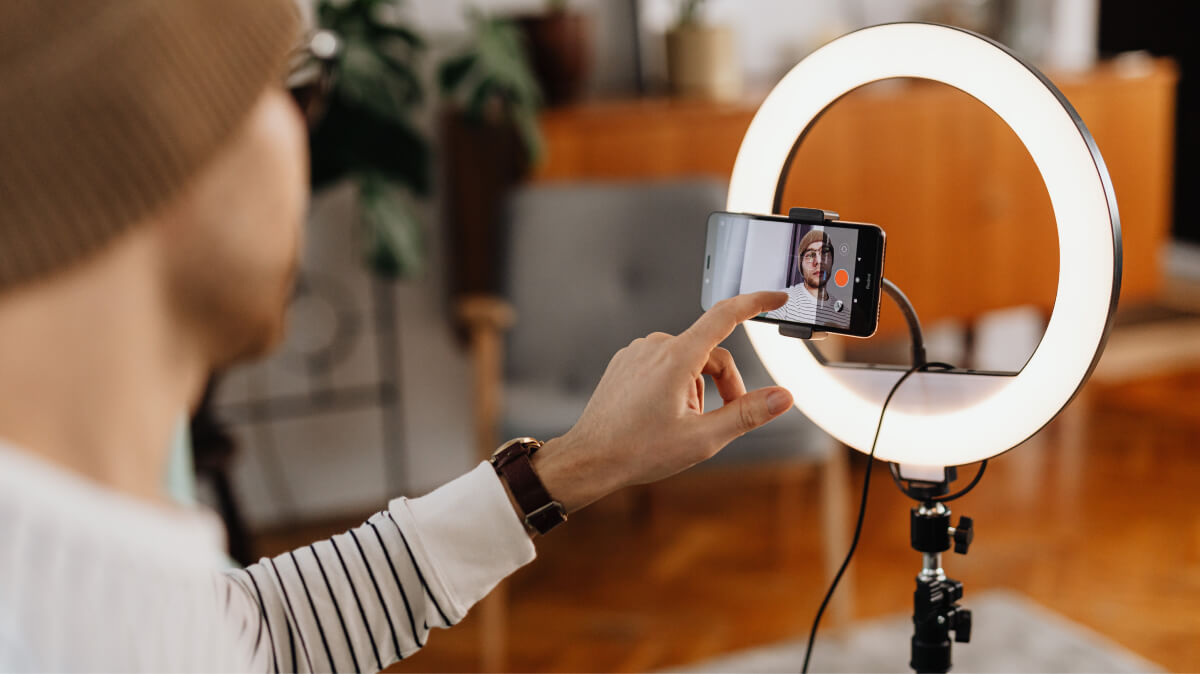 Person using ring light and smartphone for video recording or livestreaming