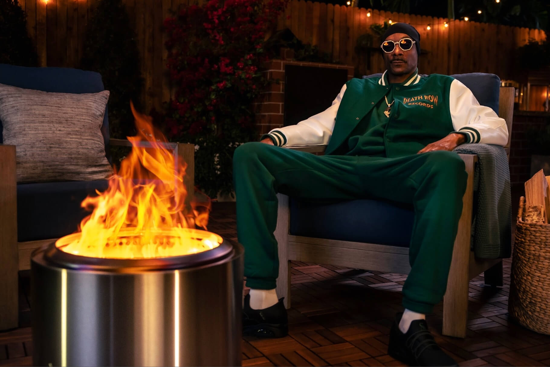 Man in Death Row Records jacket sitting by fire pit at night