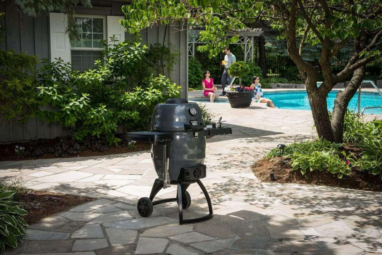 Backyard barbecue grill on stone patio with swimming pool and garden