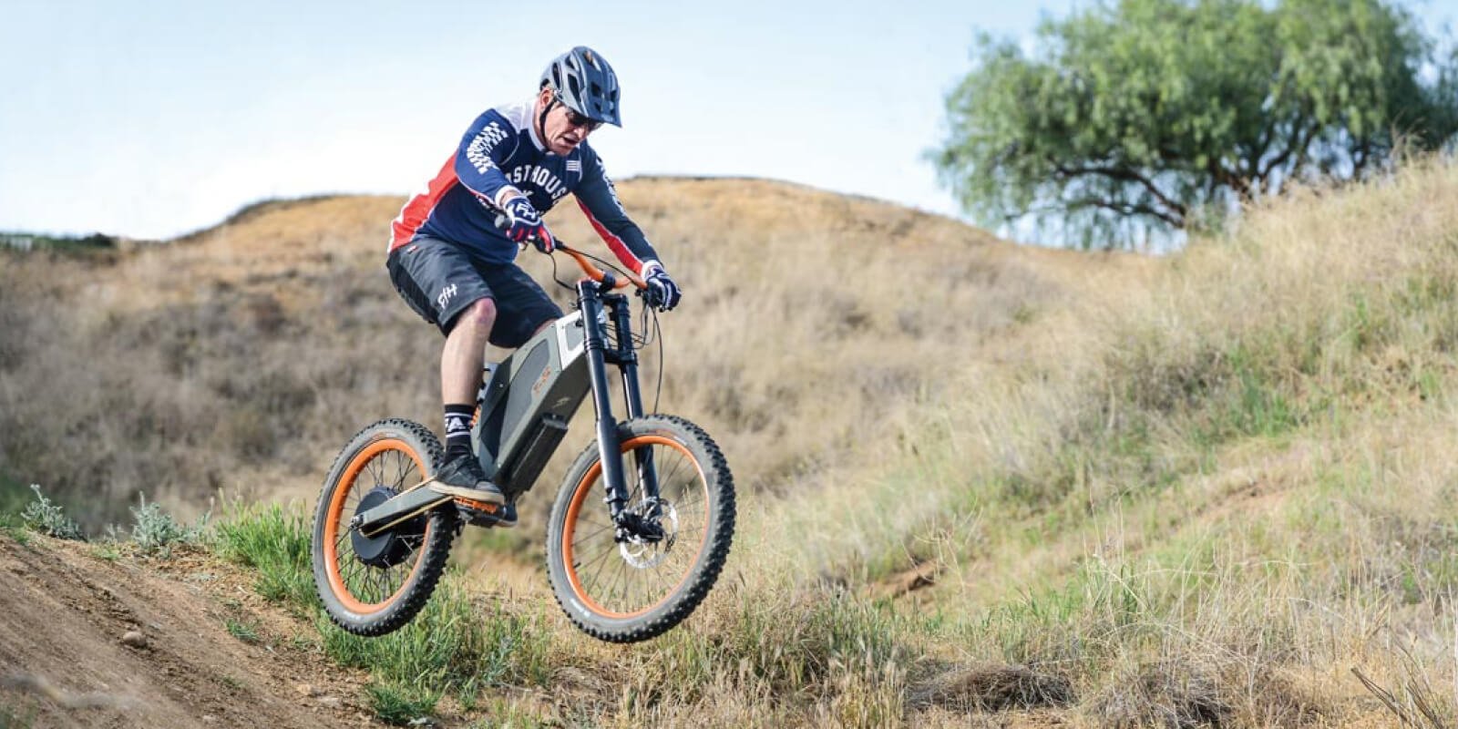 Mountain biker riding an electric bike on a rugged dirt trail
