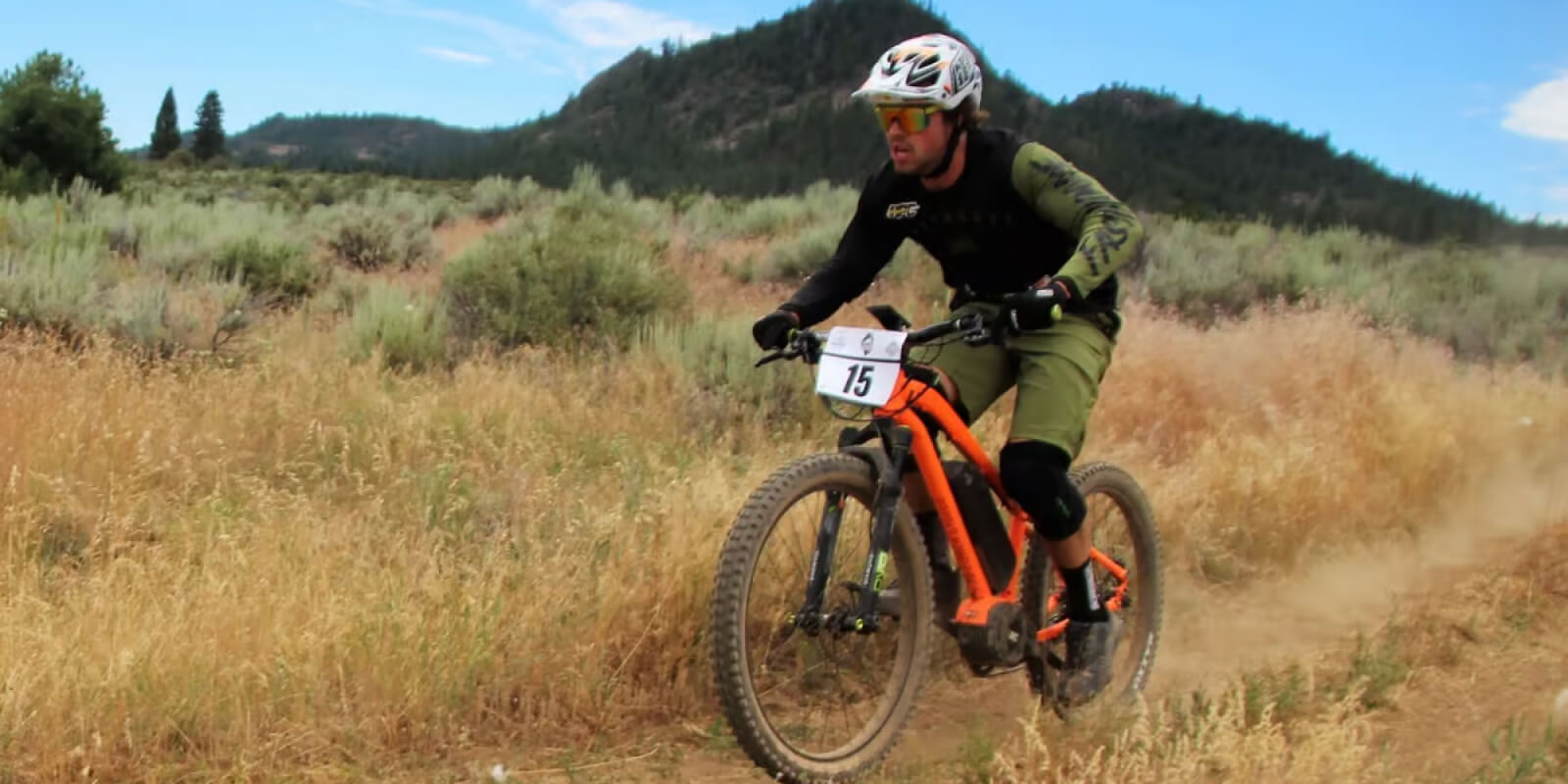 Mountain biker racing with number 15 through dusty grassy terrain