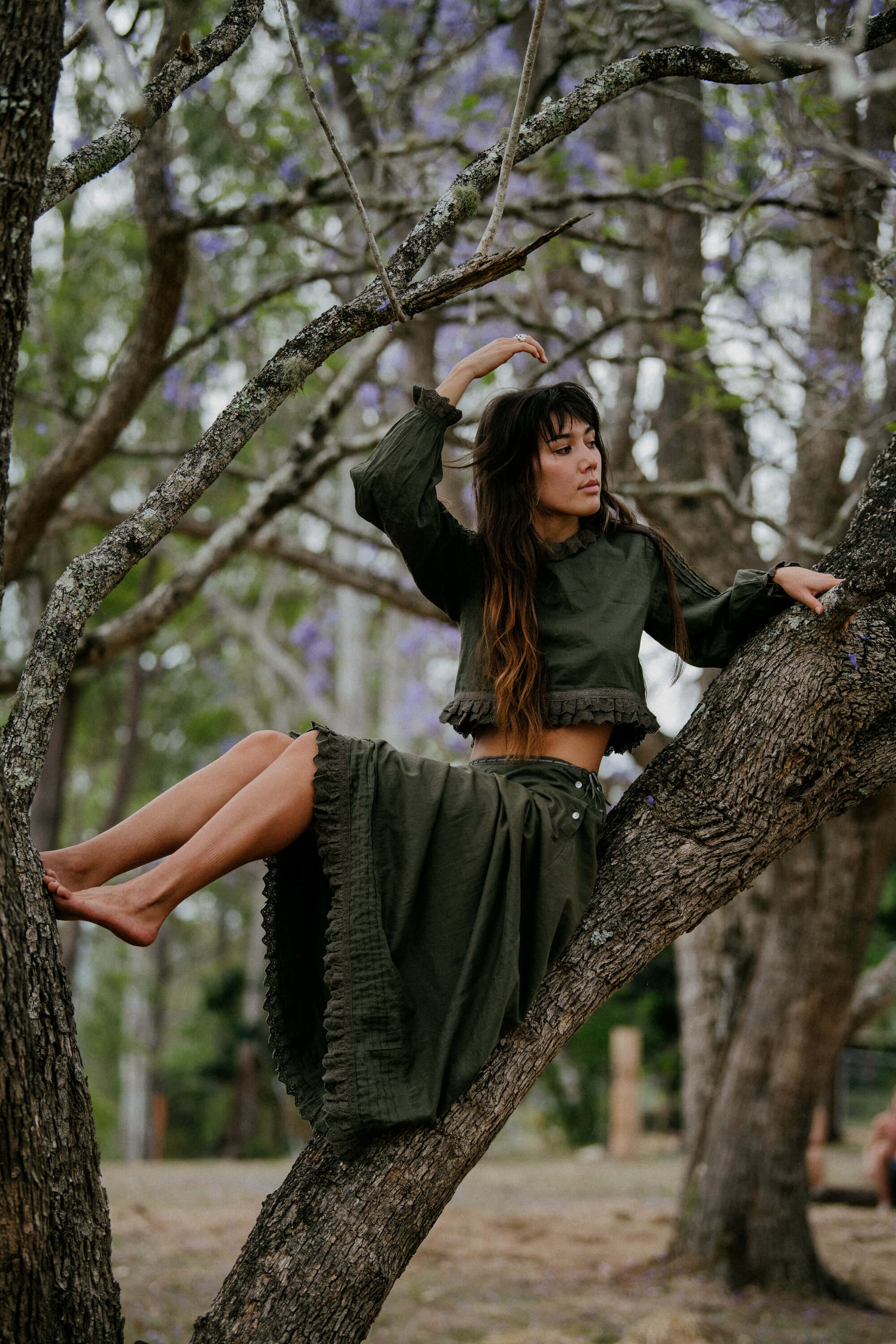 A woman sitting in a tree wearing The Silk Co dress