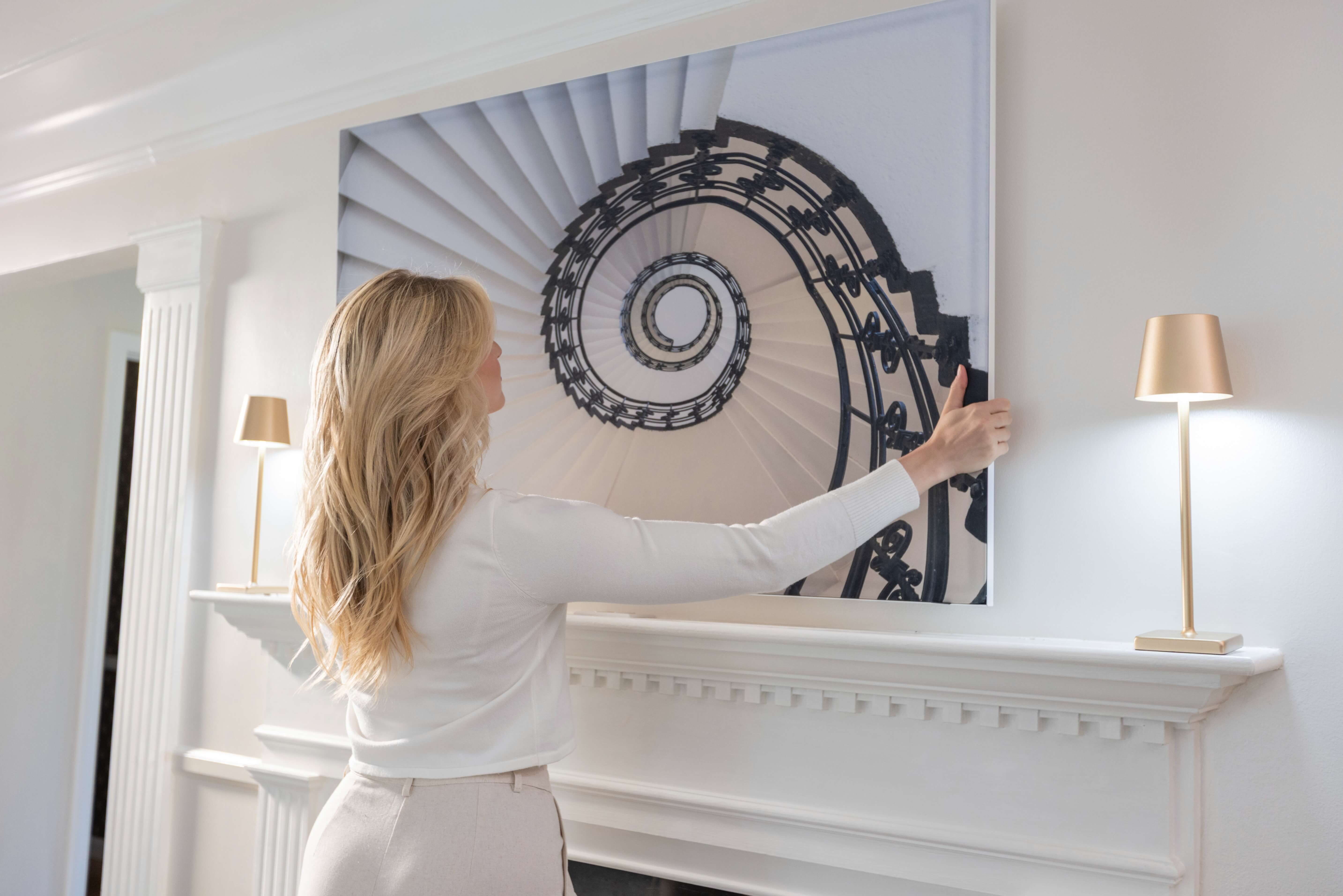 A woman putting her WallGusto painting on the wall.