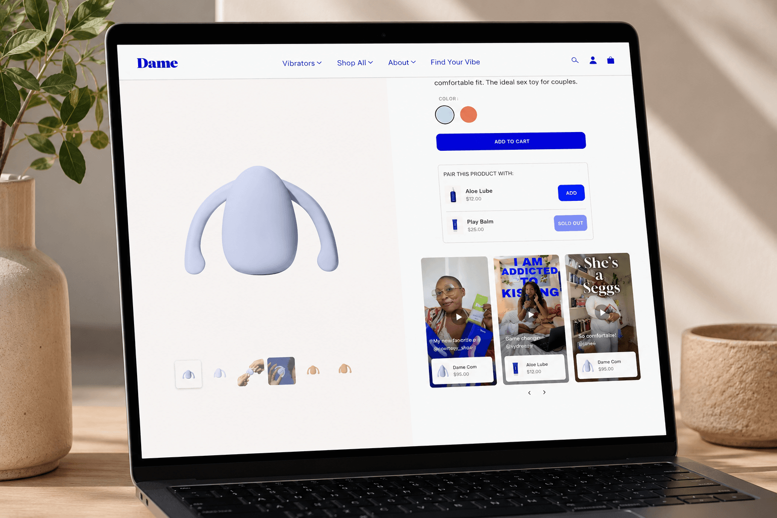 Realistic MacBook displaying a Shopify product page with a shoppable video widget embedded in the right column beneath the add-to-cart section. The widget features vertical customer testimonial videos with clickable product tags and carousel navigation, positioned above a customer reviews and star ratings section. Modern ecommerce interface with soft screen glow, neutral desk setup, warm natural lighting, and minimal workspace decor.