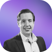 Black and white portrait of a smiling man in a suit with a white shirt against a purple gradient background.