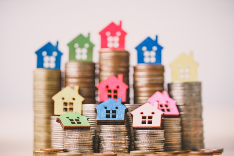 Stacks of coins topped with colorful house cutouts.