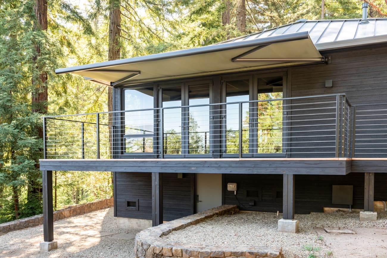 House deck with canopy awning in forest setting.