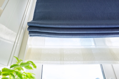 Blue Roman shades partially open above a window.