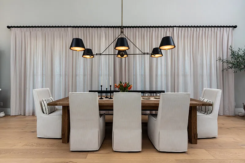 Dining room with white drapes and side panels.