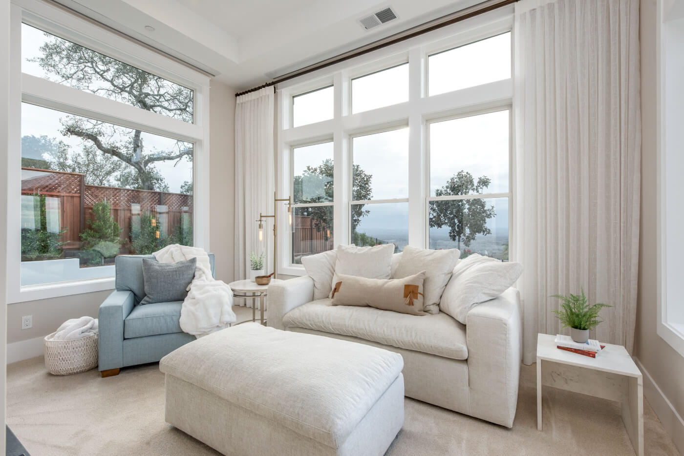 Living room with large windows, white drapes, sofa, and armchair.