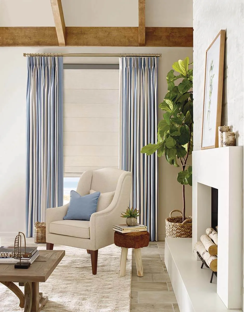 Living room with blue and white drapes, armchair, and plant.