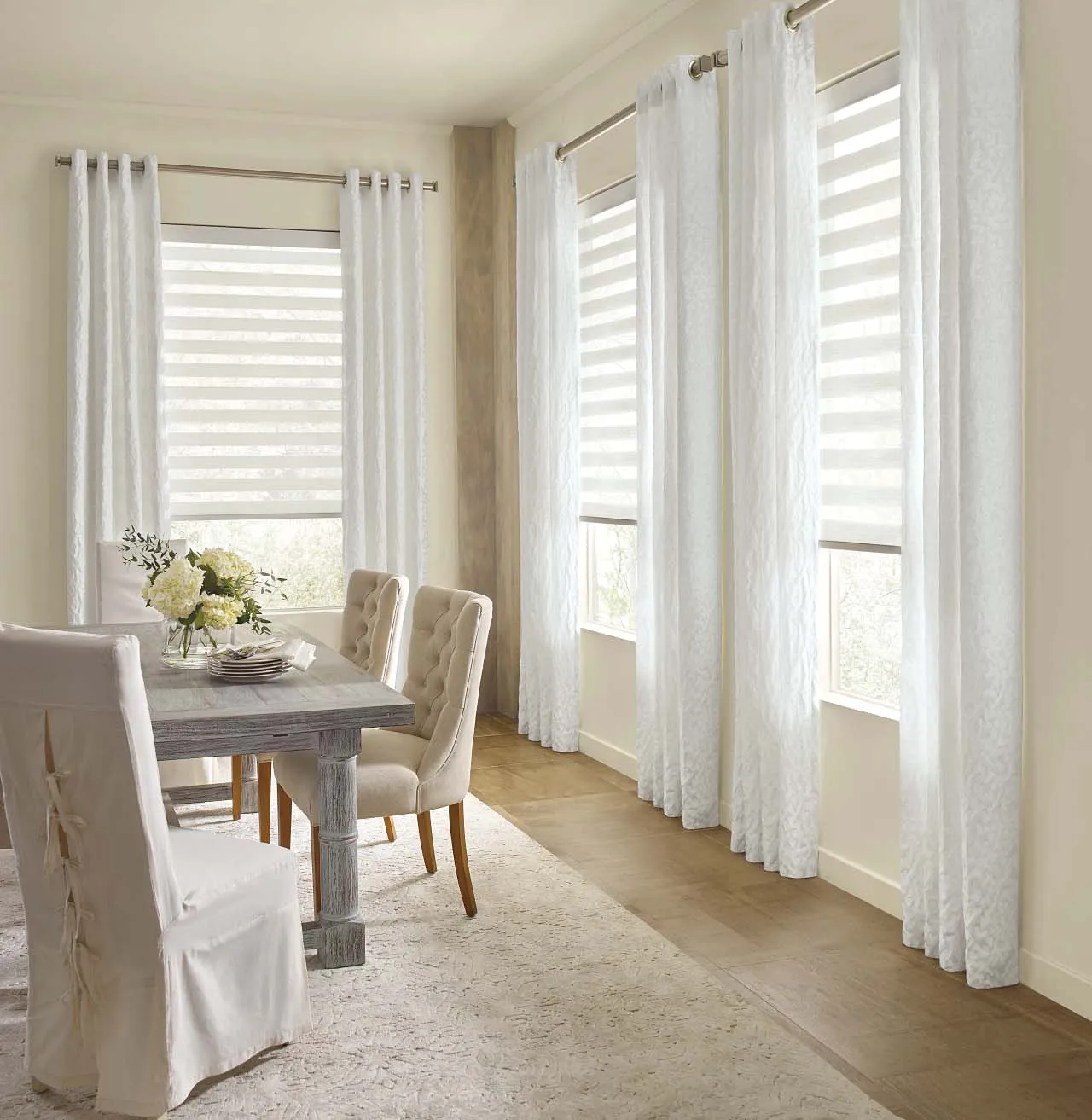 Dining room with white drapes and striped shades.