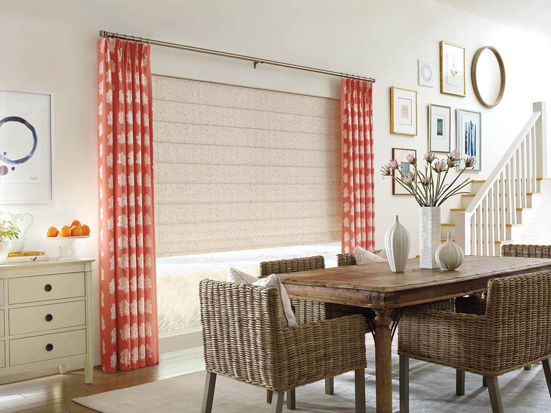 Dining room with wicker chairs, a wooden table, red patterned drapes, and side panels.
