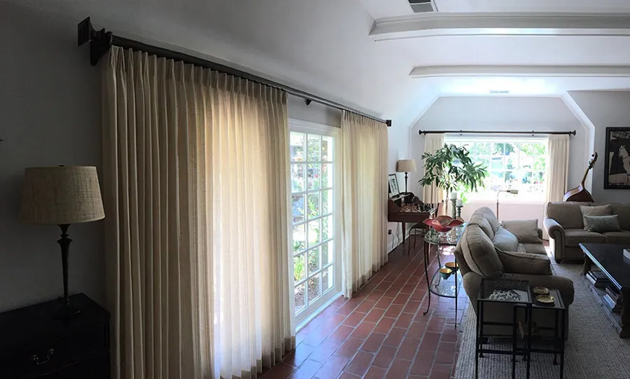 Living room with beige drapes covering windows.