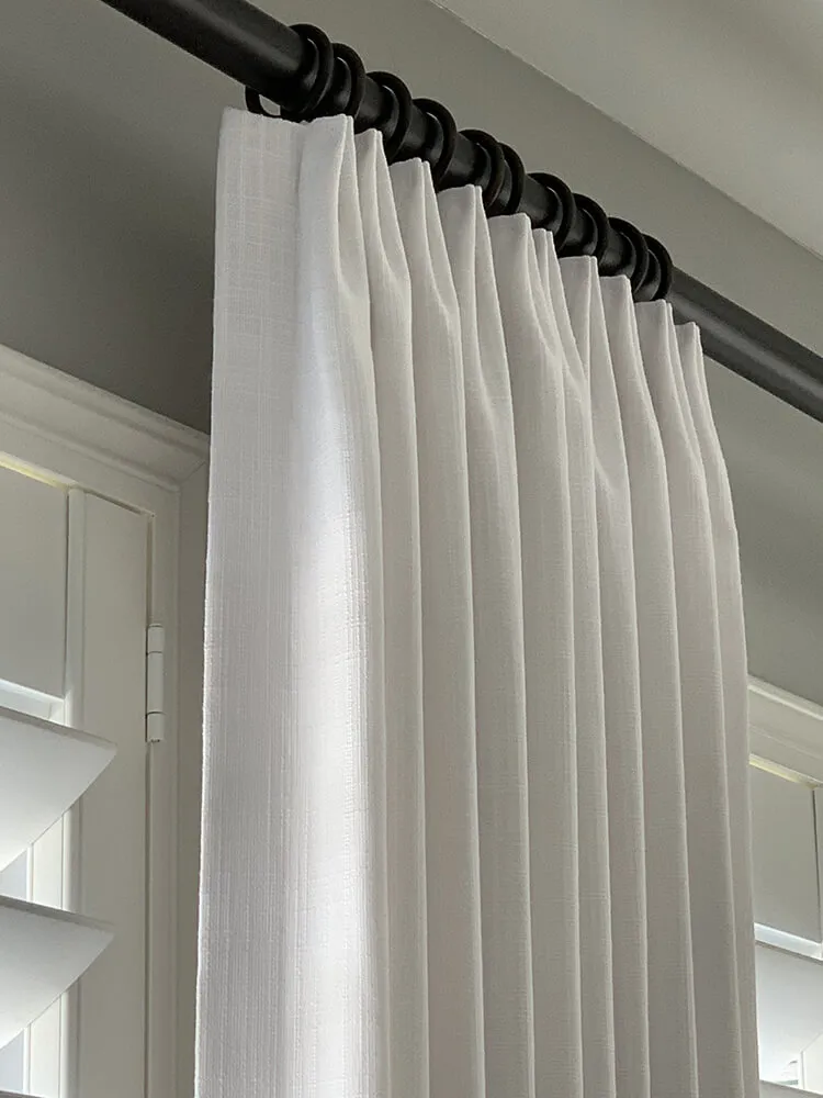 White drapes hanging on a black rod.