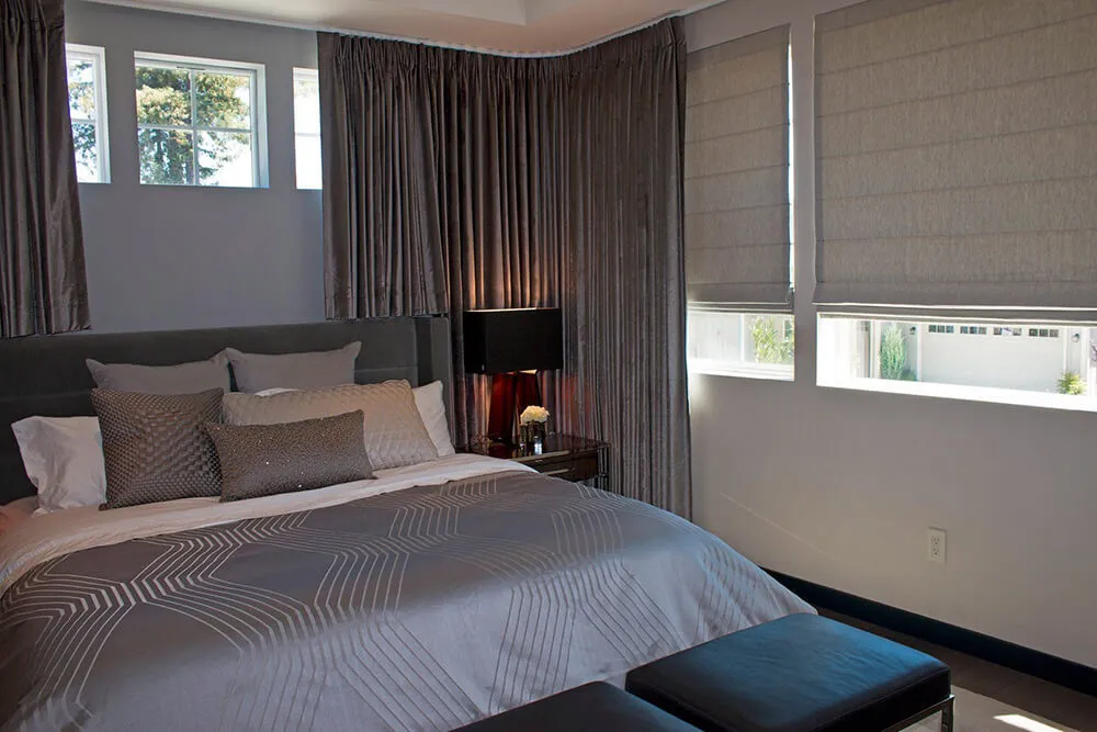 Bedroom with grey drapes and Roman shades.