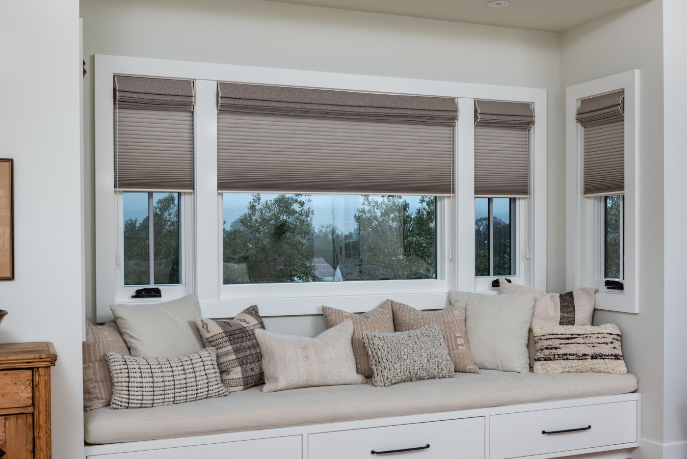 Cellular honeycomb shades and cushions on a window seat.